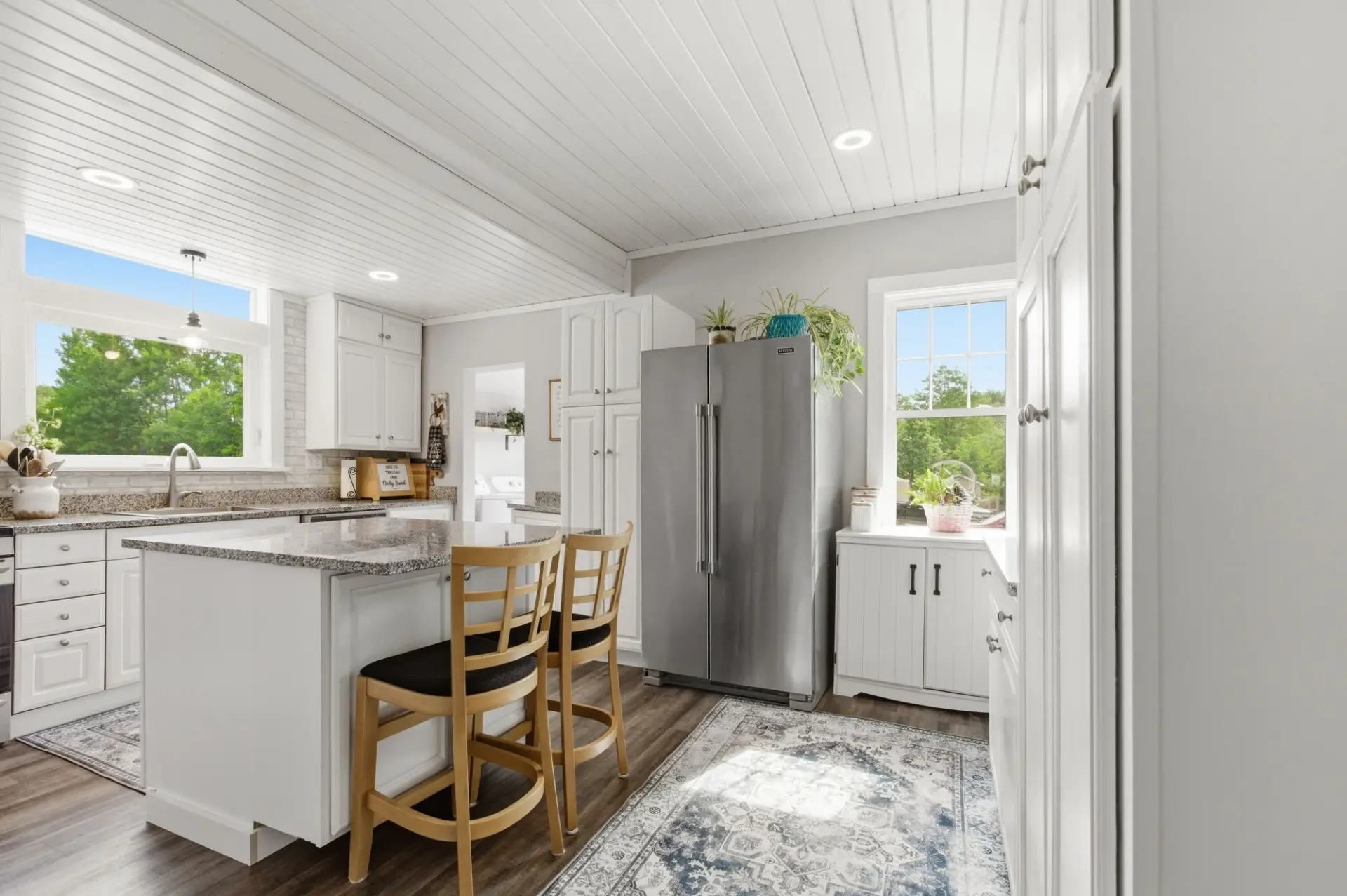Bright white kitchen with granite island, bar stools and natural light in an Erie area home